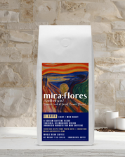 Specialty coffee bag for Max Caffeine light roast with miraflores branding and art masterpiece The Scream by Edward Munch, set against a stone wall background