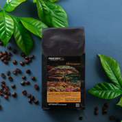 Bag of African espresso premium blend high quality coffee beans from Miraflores Coffee showing flavor notes of blueberry, currant and caramel. Bag is set alongside roasted coffee beans on.a white background