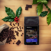 Bag of French Roast coffee from Miraflores Coffee Co. showing art of the seine and eiffel tower, bag is set alongside roasted coffee beans, on a wooden table with plants 