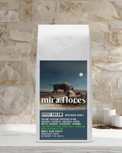 Specialty coffee bag for a dreamy dark roast espresso made from beans from Africa. Bag has Miraflores Coffee branding and features art masterpiece The Sleeping Gypsy by Henri Rousseau, set against a stone wall background