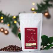 A pack of Miraflores Pecan Pie Flavored Coffee with a medium roast level. The packaging is white with a red label and a graphic of a nazca line and details about the flavor profile, with festive ornaments